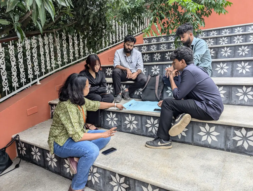 Group of people sitting on steps discussing a drawing
